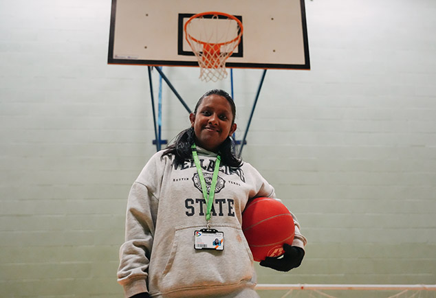 Person holding ball in front of indoor basket ball hoop