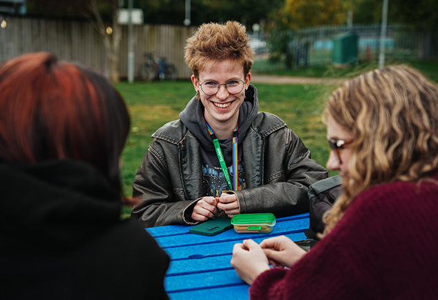 Students sitting outside on bench talking 