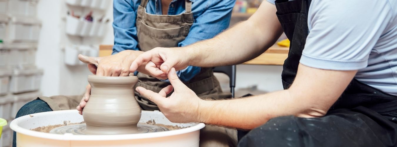 Two people working with pottery wheel 