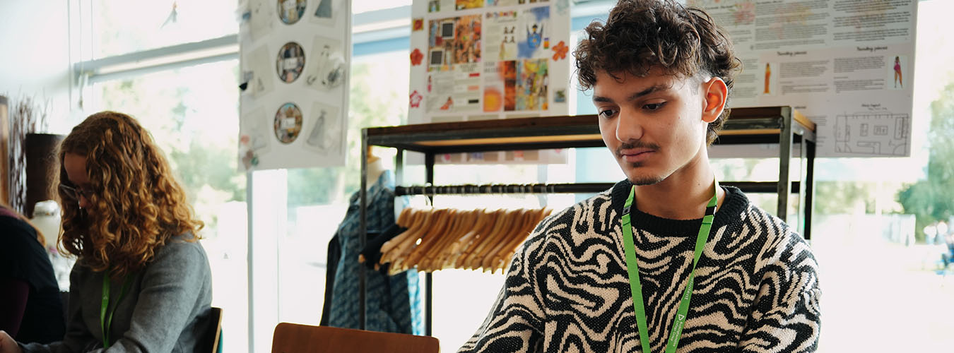 Student working in fashion classroom with clothes rail in background