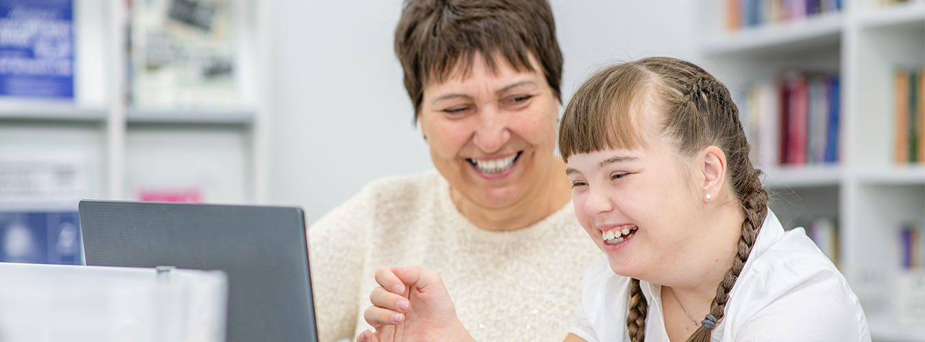 Young person sitting next to an adult smiling