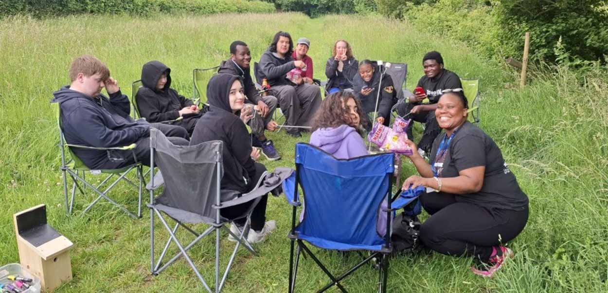 Group of young people sitting in circle on camping chairs