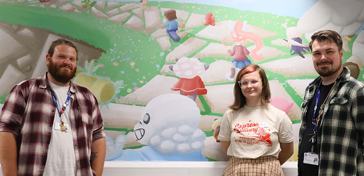 Artist Isabella standing with Game tutors in front of wall art